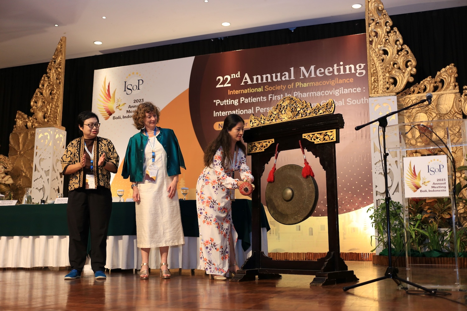 Angela Caro-Rojas, President of ISoP, strikes the gong to announce the official opening of ISoP 2023, while Grace Wangge, the chair of the local organising committee for ISoP Bali, and Mira Harrison-Woolrych, the chair of the scientific committee, look on